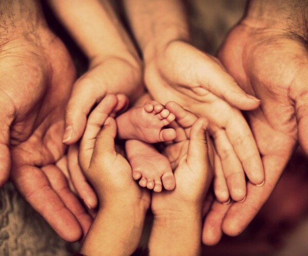 hands of father, mother, daughter keep little feet baby