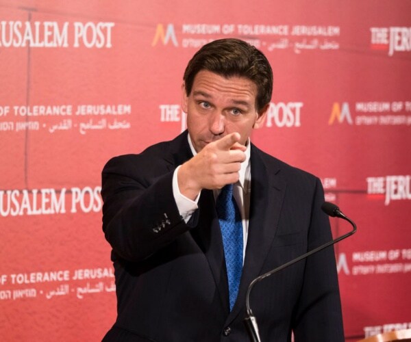 ron desantis in suit points with jerusalem post background