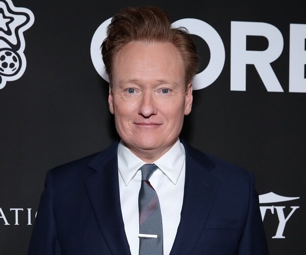 conan obrien stands on red carpet