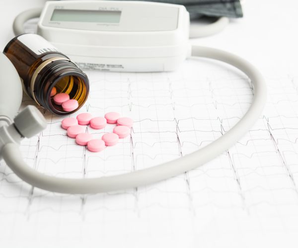 blood pressure equipment and pills on paper cardiogram