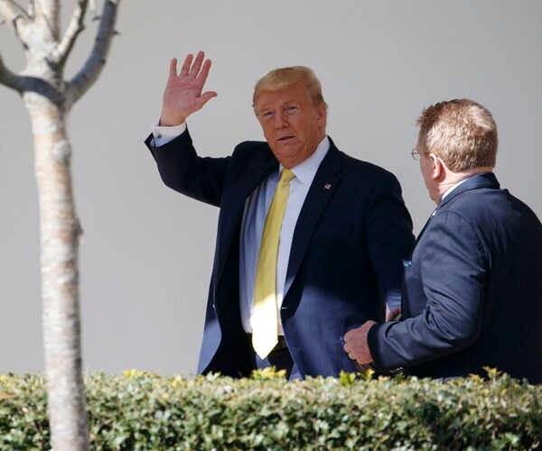 president donald trump walks along the colonnade at the white house and waves to reporters