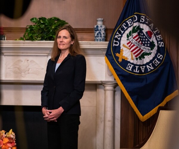 amy coney barrett in front of a flag