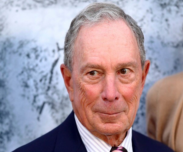 michael bloomberg looks to his right and smirks