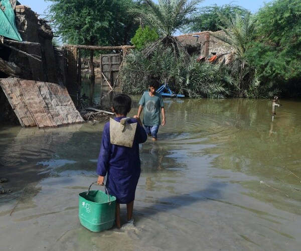 people wade outside their flooded houses