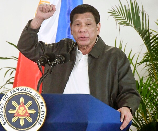president rodrigo duterte holds up a fist while speaking at a press conference