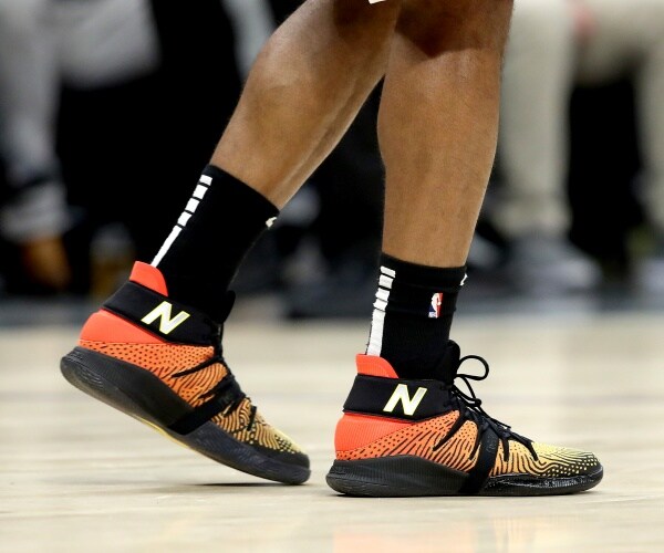 orange new balance shows with black and white socks worn by a basketball player