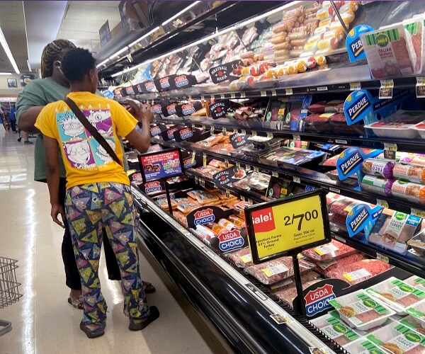 people shop in meat section of grocery store
