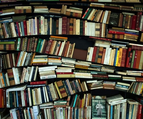 curved bookshelf with books stacked vertically and horizontally