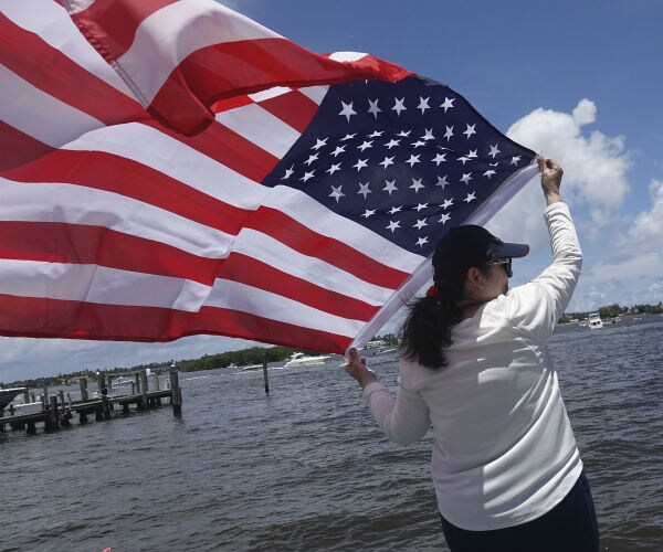 a woman is shown waving a us flag as she overlooks boats in the water in palm beach, florida