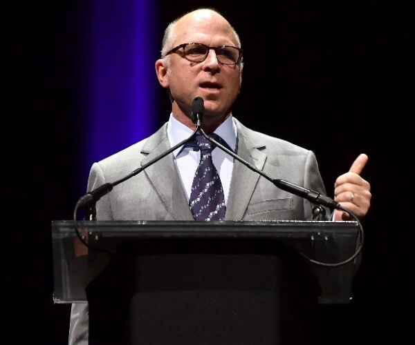 Bob Berney is seen speaking to an audience in a gray suit, dress shirt and tie