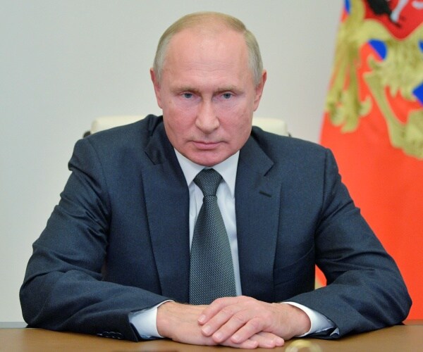 vladimir putin sits at table