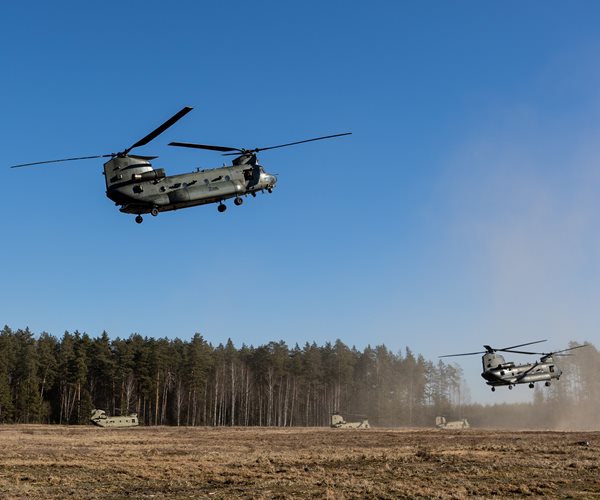 Two helicopters landing in a field.