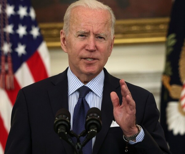 joe biden stands in front of flags and speaks