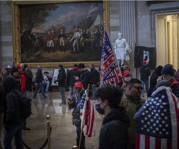people walk in the capitol rotunda with trump flags