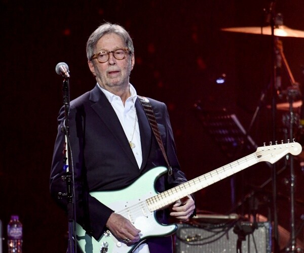 clapton playing a guitar on stage