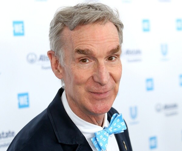 bill nye stands on blue carpet