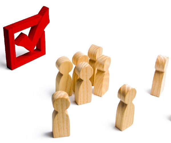 wooden peg people looking at a checkmark in a box
