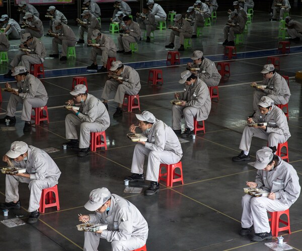 workers in wuhan, china, eat lunch apart from each other to control the spread of COVID-19