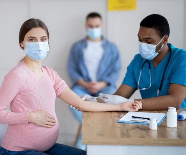 pregnant woman looking at camera while receiving the COVID vaccine