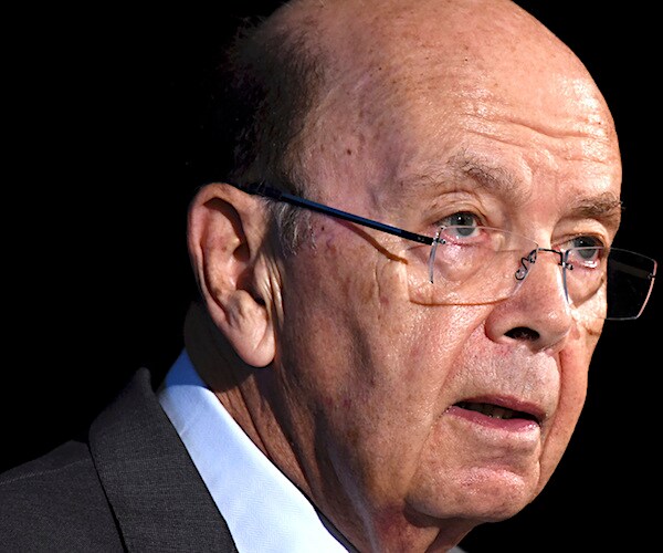wilbur ross leans forward and listens during a news conference