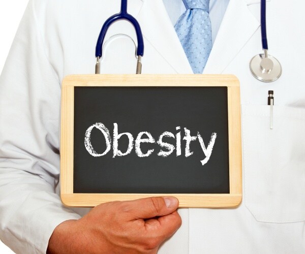 doctor holding up a blackboard with obesity written on it