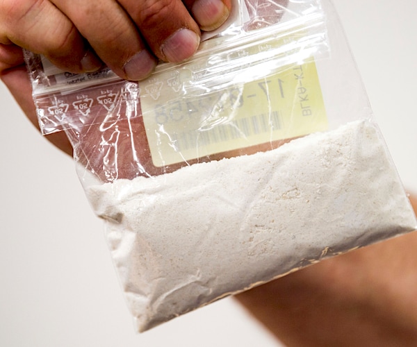 a bag of confiscated cocaine is held up by the right hand of a man