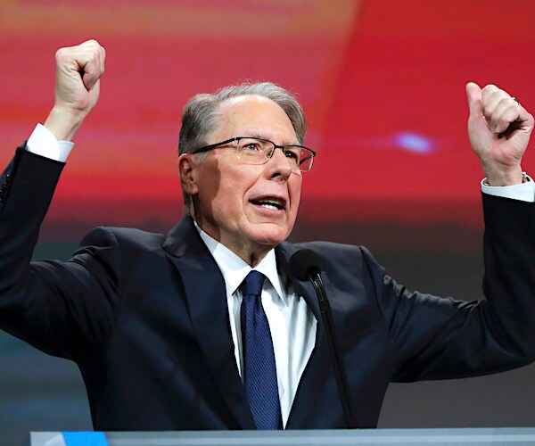wayne lapierre raises his hands over his head during a speech