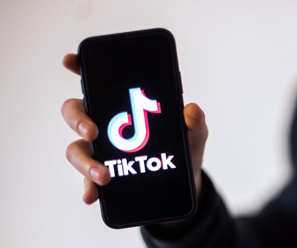 hand holding phone showing tiktok logo