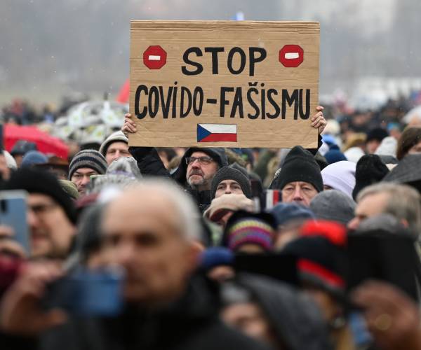 A man holds up a sign reading Stop Covid Fascism during a protest