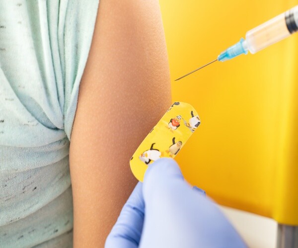 close up of a syringe and child's arm and kid band-aid