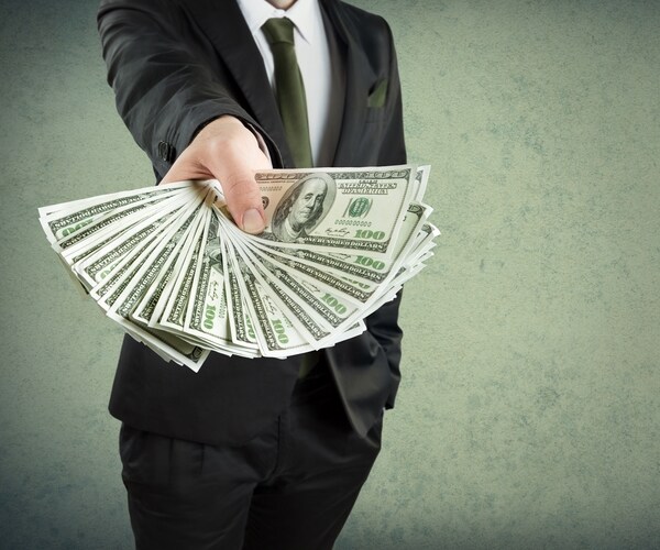  Personal loan symbolized by business man thrusting handful of dollars bills in your direction