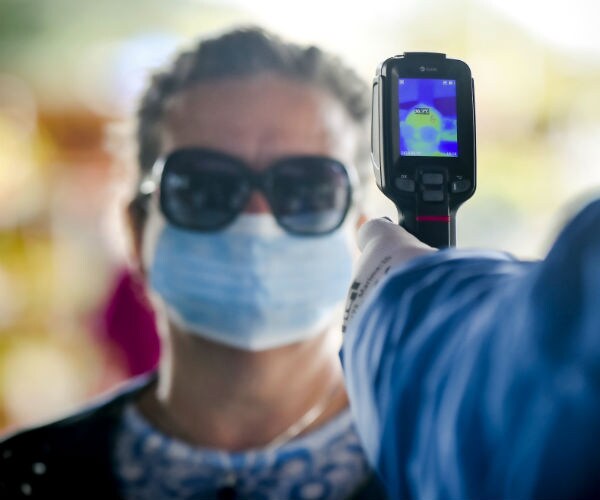 a woman is shown getting a temperature check before entering a market
