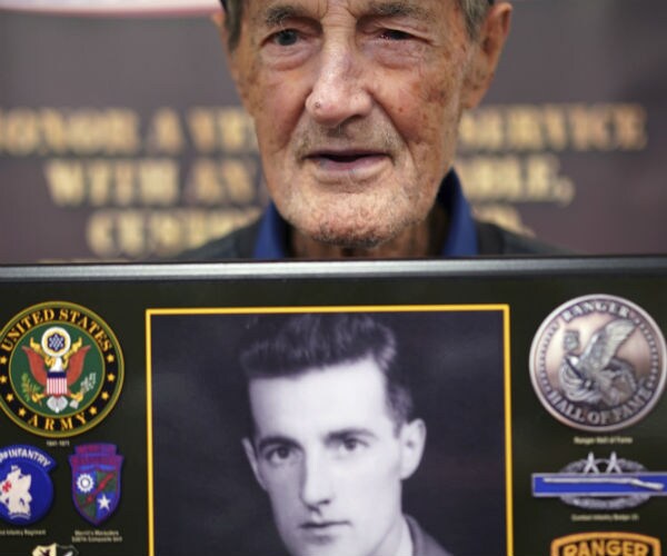 gilbert howland holding a plaque bearing a younger photo of himself