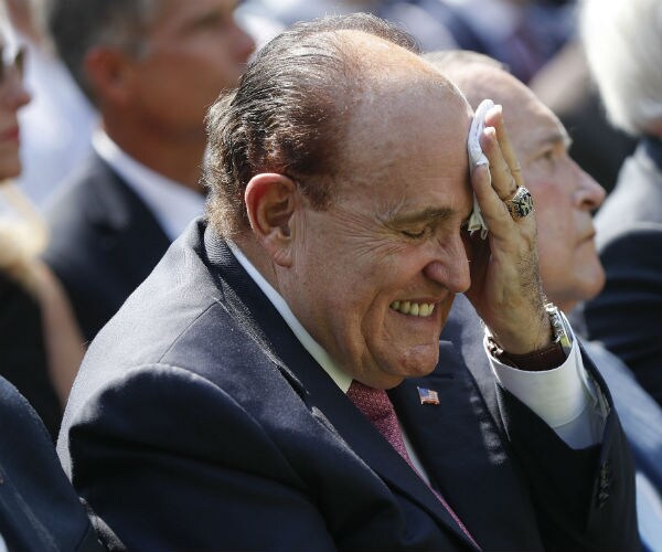 rudy giuliani is shown wipping his forehead with a hankerchief