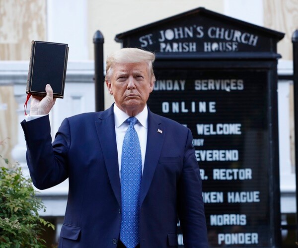president trump holds up a bible during a photo op in front of a church