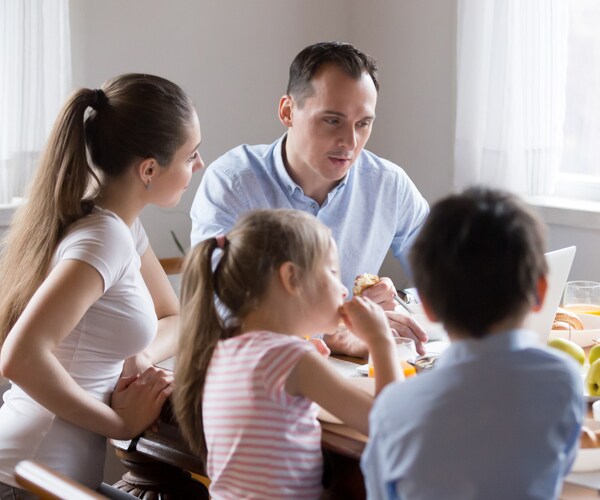 a family sitting at a table and eating breakfast