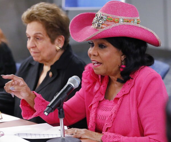 frederica wilson is shown wearing her signature hat in pink with matching suit and earrings