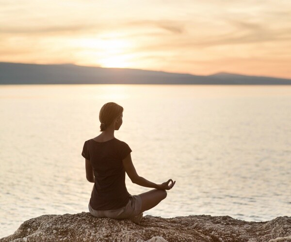 woman meditating during a sunset