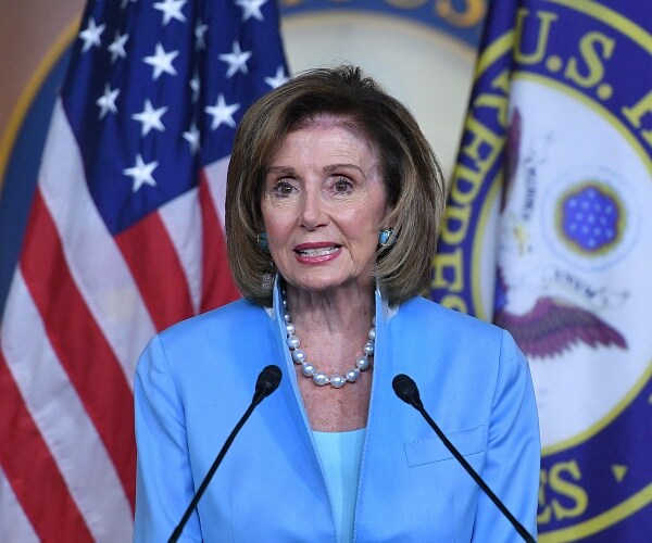 nancy pelosi stands behind podium