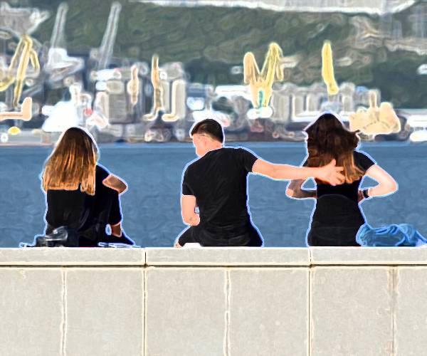 a guy sits between two young women with his hand on the back of one of them
