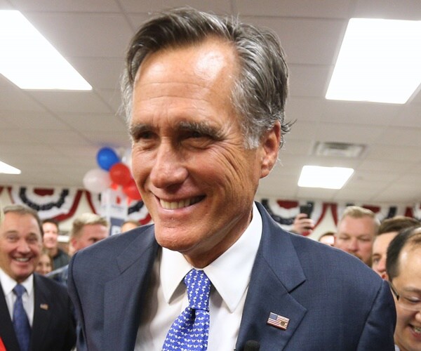 mitt romney smiles while talking amid a throng of reporters