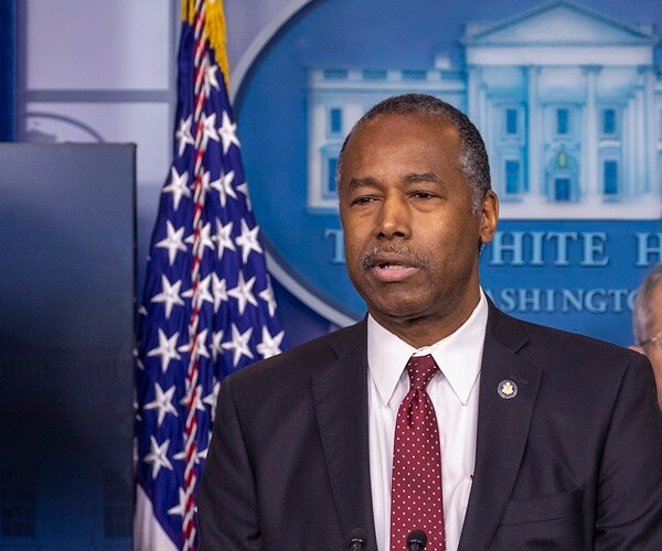 ben carson stands in front of white house logo and speaks at a podium
