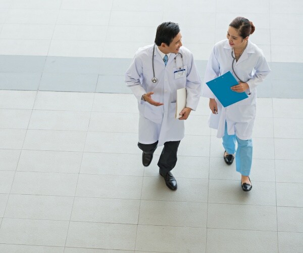 Two physicians consulting as they walk outside medical building