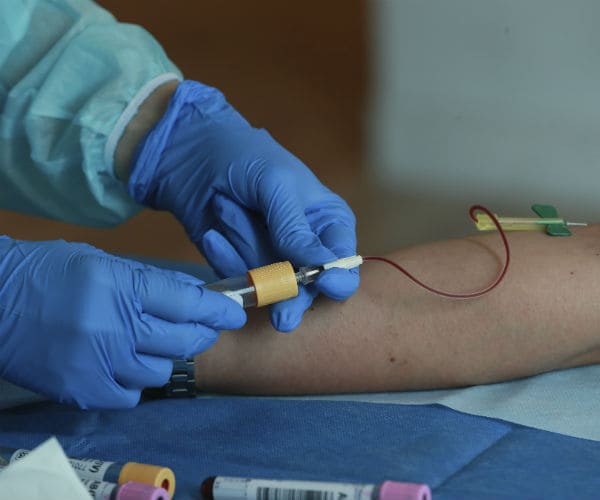 A medic collects blood from a patient for antibodies to the coronavirus disease testing at a clinic