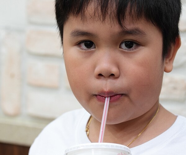 a body holding a cup and drinking through a straw