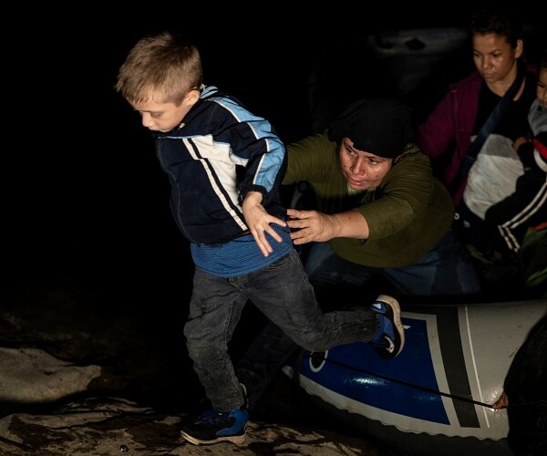 boy steps off raft onto shore at night