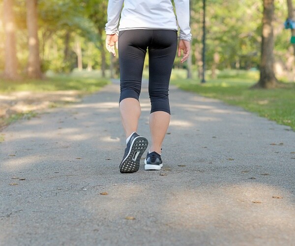 woman taking a walk outside surrounded by trees