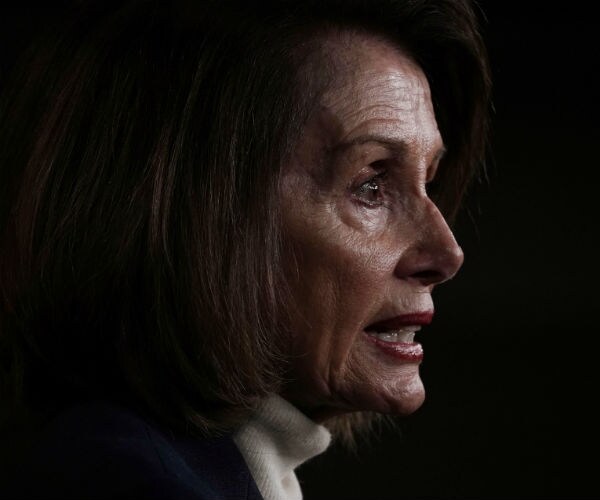 house speaker nancy pelosi is seen from the right side of her face as she faces to the right amid a shadowy backdrop