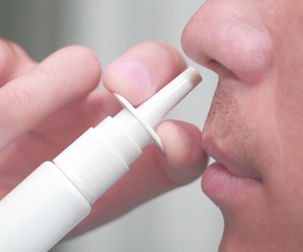 close-up of man using nose spray