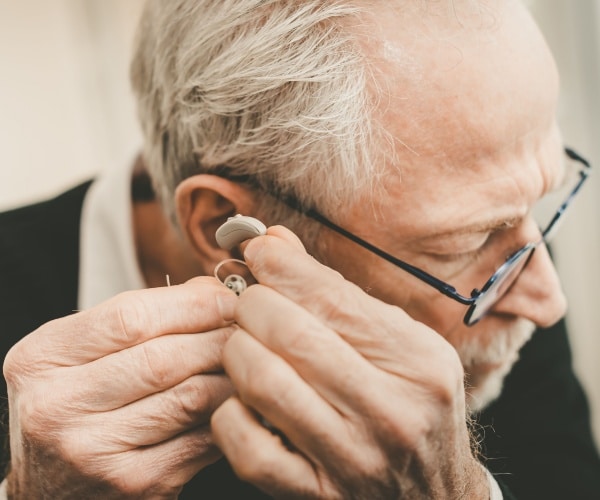 man putting a hearing aid in his ear